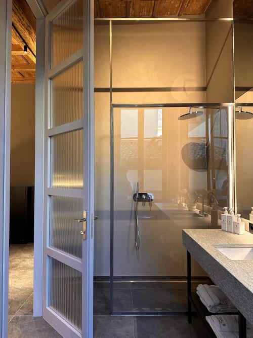 Bagno moderno nell'appartamento Casa_B Como City con cabina doccia in vetro e vista sulla città di Erba