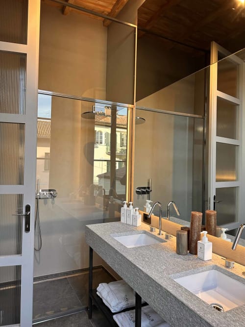Bagno moderno dell'appartamento Casa_B Como City con doppi lavandini, ripiano grigio, doccia walk-in e vista sulla città di Erba