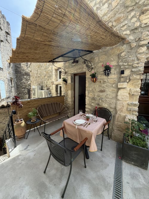 Charmante Steinterrasse des Ferienstudios "Occitan Heritage" in La Sarrasine in Aiguèze, die Ardèche ist in 3 Gehminuten erreichbar, mit Esstisch, Sonnensegel und historischer Architektur.