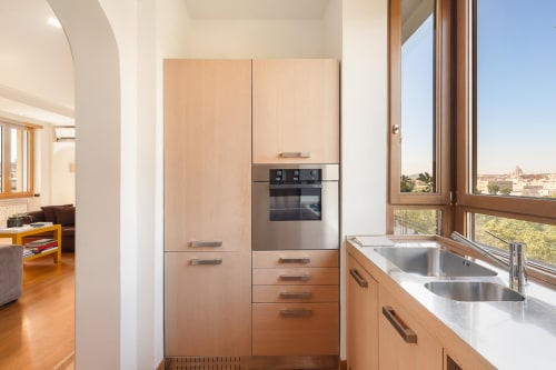 Modern kitchen with wooden cabinets, stainless steel appliances, and city views at Terrestre Roma apartment in Rome