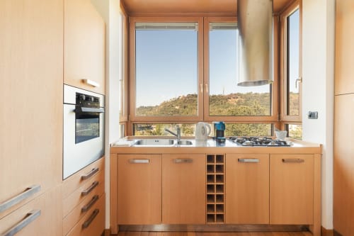 Modern kitchen in Casa Flaminio apartment at Terrestre Roma with wooden cabinets, stainless steel sink, gas cooktop, and