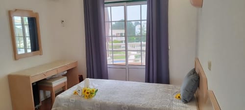 Quarto claro em Sweet Home Estrela do Vau em Portimão com cama, escrivaninha e portas-balcão com vista para a área de piscina