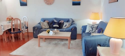 Sala de estar iluminada do apartamento Sweet Home Estrela do Vau com sofá azul, cadeiras de jantar, mesa de madeira e luminárias amarelas