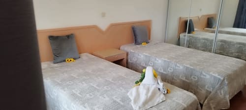 Dois leitos com cabeceiras laranja e decorações de flores amarelas no apartamento Sweet Home Estrela do Vau, Portimão