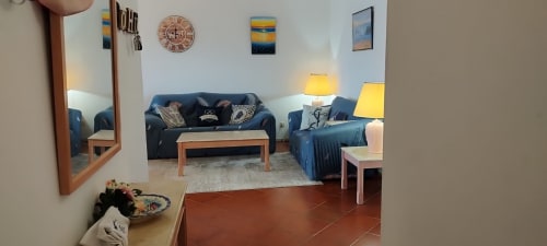 Sala de estar aconchegante do apartamento Sweet Home Estrela do Vau em Portimão, com sofá azul, móveis em madeira e luminárias amarelas