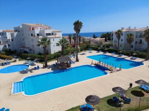 Complexo de apartamentos Sweet Home Estrela do Vau em Portimão com piscinas azuis, palmeiras, edifícios brancos e vista para o Mar Mediterrâneo