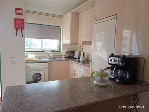 Kitchenette clara no apartamento Sweet Home Estrela do Vau, Portimão, com armários bege, eletrodomésticos de bancada e máquina de lavar