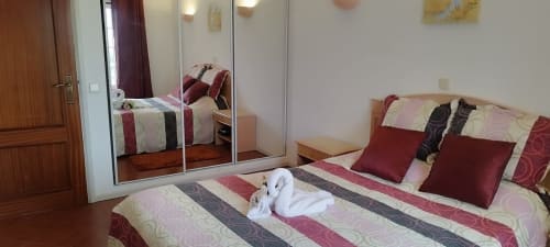 Quarto moderno em Sweet Home Estrela do Vau com roupa de cama listrada, almofadas bordô e guarda-roupa espelhado em Portimão