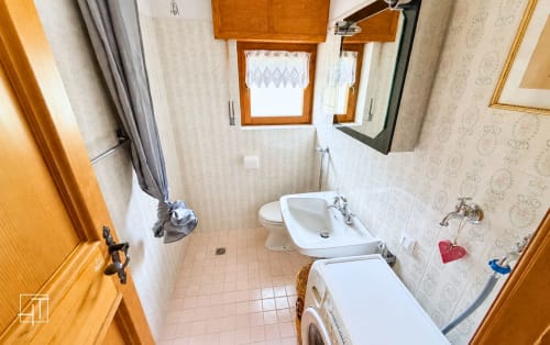 Bathroom in Cortina d'Ampezzo apartment with white sink, toilet, bidet, and shower with curtain