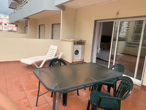 Terraço do apartamento Sweet Home Casa dos Arcos em Portimão com mesa de jantar, cadeiras, espreguiçadeira e máquina de lavar