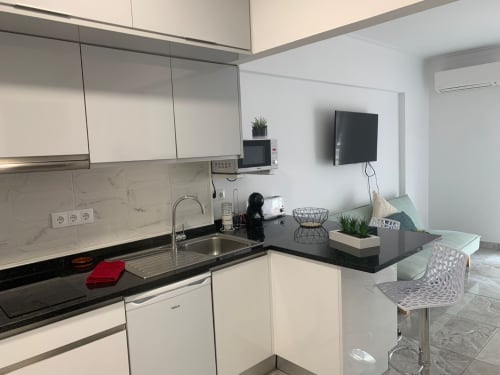 Kitchenette moderna no apartamento Sweet Home Casa dos Arcos em Portimão, com armários brancos, bancada preta e área de refeições