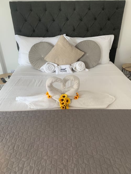 Cama elegantemente decorada no apartamento Sweet Home Casa dos Arcos com lençol branco, almofadas decorativas e girassol
