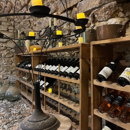 Cave à vin du Domaine du Fortin à Ménerbes avec casiers bois, bouteilles et éclairage ambré sur pierre
