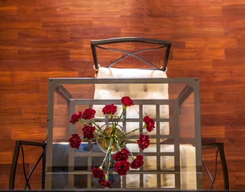 Red carnations in glass vase on dining table with wooden floors in Madrid apartment