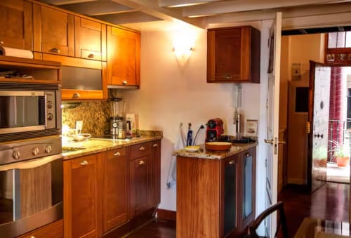 Modern kitchen with wood cabinetry, granite counters, and stainless steel appliances in Madrid apartment