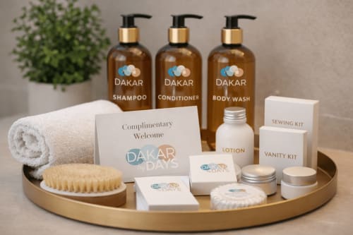 DakarByDays welcome amenities kit with shampoo, conditioner, body wash, lotion, towel, and toiletries.