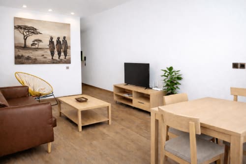 Modern apartment living room at DakarByDays with wood furniture, TV, plants, and African artwork