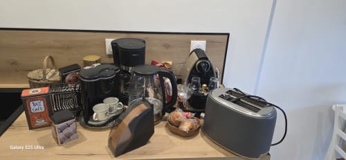 Kitchenette d'un studio avec cafetière, grille-pain, bouilloire et petit-déjeuner sur plan de travail en bois