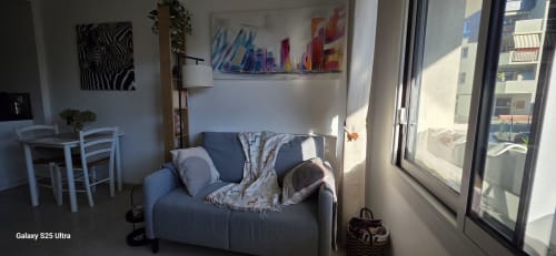 Studio lumineux à Zoppas Aix-les-Bains avec canapé bleu, table de salle à manger blanche, œuvres d'art contemporain, vue sur la ville