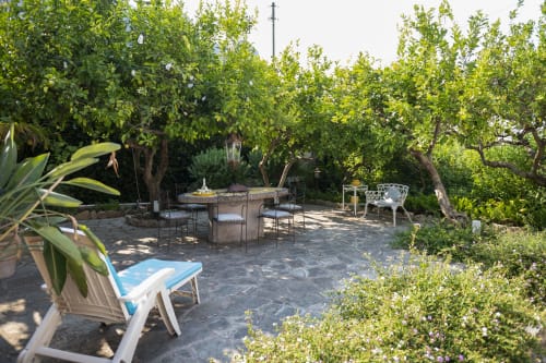 Giardino mediterraneo rigoglioso con terrazza, zona pranzo, poltrona relax e vista mare alla villa La Capperina di Capri