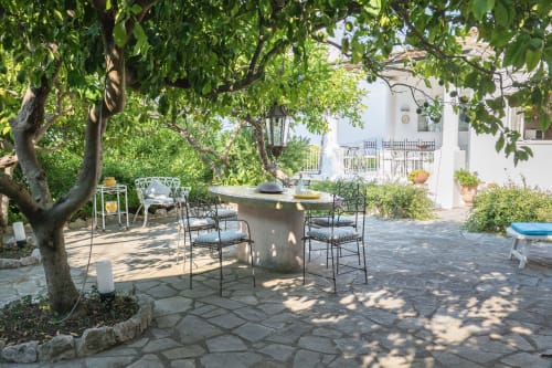 Area patio ombreggiata di Villa La Capperina a Capri con tavolo da pranzo, sedie e alberi rigogliosi