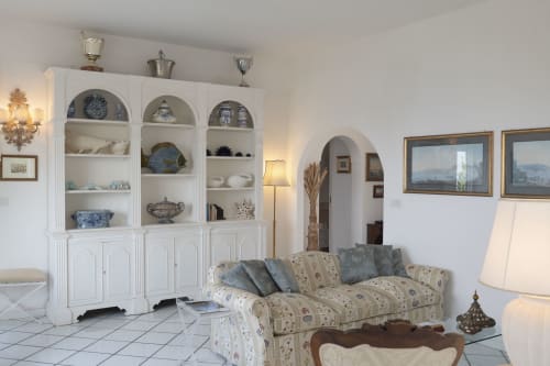 Elegante soggiorno di Villa La Capperina a Capri con mobili bianchi, divano decorato e dipinti con vista mare