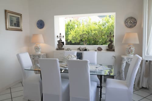 Elegante sala da pranzo della villa La Capperina a Capri con vista mare da ampia finestra, sedie bianche, tavolo in vetro