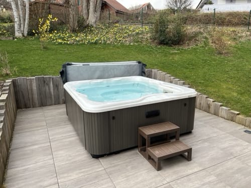 Bain à remous extérieur aux eaux turquoise sur terrasse en bois de la villa Le Chalet les Roitelets à Gérardmer