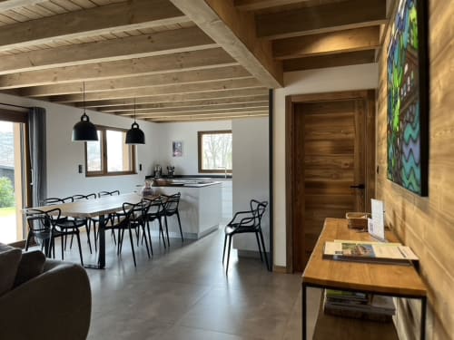 Intérieur moderne du Chalet les Roitelets : salle à manger, chaises noires, poutres en bois et cuisine