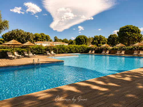 Funkelndes blaues Schwimmbecken mit Holzterrasse, Liegen und Sonnenschirmen im Luxushotel Calarossa By Sarai in Lecci, Korsika