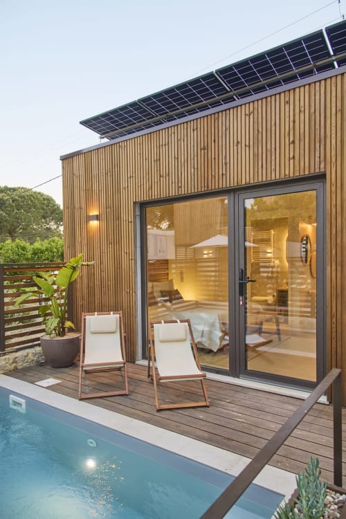 Casa Redonda Aroeira com piscina, painéis solares, espreguiçadeiras no deck e portas de vidro com vista para a piscina