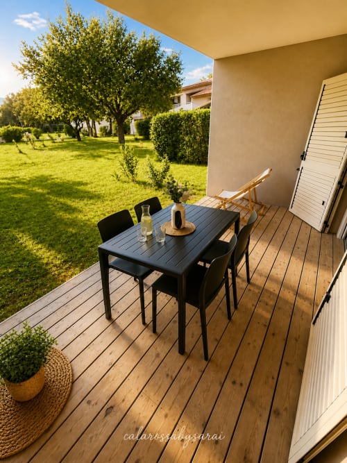 Wooden terrace at Calarossa By Sarai with black dining table, chairs, lounger, and garden view in Lecci