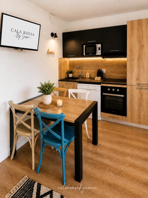 Modern kitchen and dining area at Calarossa by Sarai apartment in Lecci with wooden table, blue chairs, and equipped