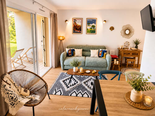 Bright garden-view apartment at Calarossa By Sarai with green sofa, dining area, outdoor terrace access, and modern amenities