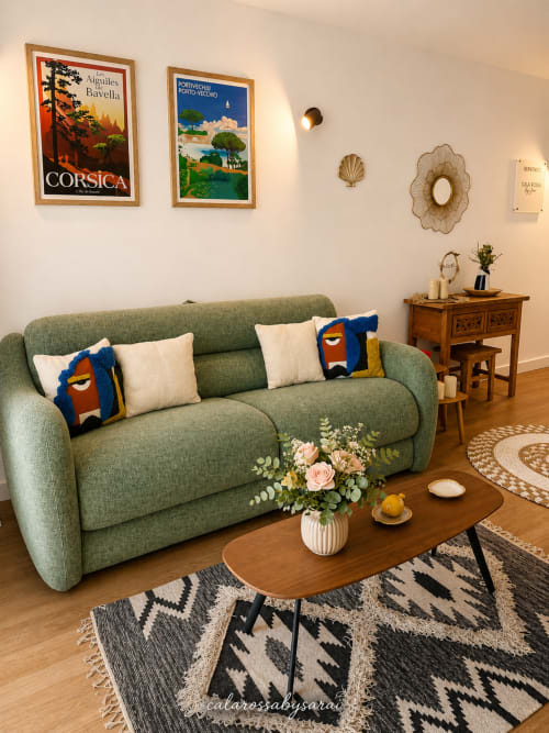 Green sofa with cushions in Calarossa By Sarai apartment, Lecci, with wooden coffee table and travel posters on white wall