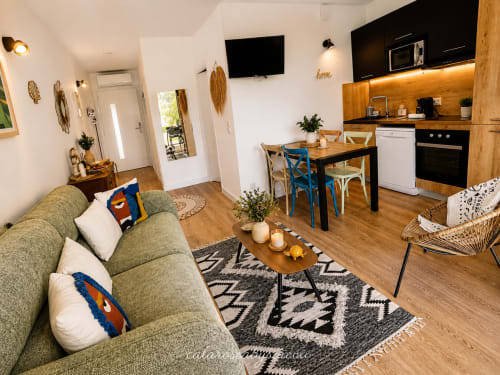 Modern open-plan apartment at Calarossa By Sarai with green sofa, dining area, kitchen, and wooden floors in Lecci