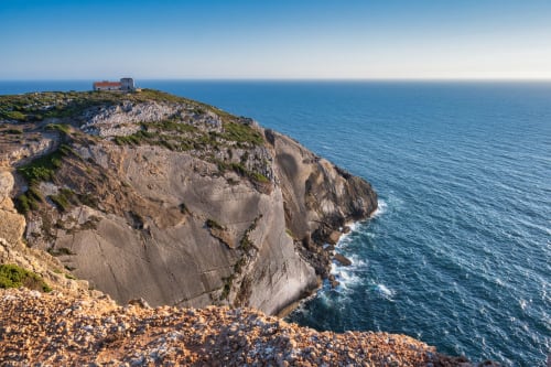 Penhascos dramáticos com torre histórica em Casa Redonda Aroeira, Portugal com vista para o oceano azul