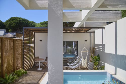 Pátio da Casa Redonda Aroeira com piscina, rede, pérgola branca e divisórias de madeira em Portugal