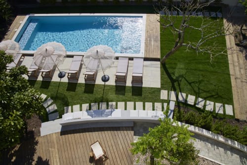 Vista aérea da área de piscina da Casa Redonda Aroeira com espreguiçadeiras, guarda-sóis e assentos curvos em Aroeira, Portugal