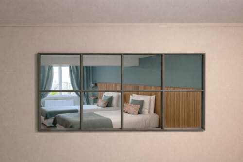 Grande armoire miroir reflétant la chambre de l'Hôtel De Lion Sur Mer, avec lits, oreillers et mur d'accent bleu-vert