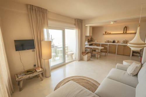 Modern hotel room at Escanda Building Solutions with beige sofa, TV, kitchenette, and balcony view in Spain