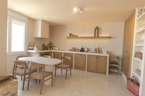 Modern hotel kitchen at Escanda Building Solutions with wooden cabinetry, white countertops, dining table, and shelving in
