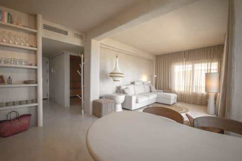 Modern hotel suite with white sectional sofa, dining table, pendant lighting, and beige curtains at Escanda Building