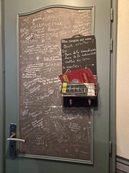 Tableau noir au mur de l'hôtel Orval Et Sens à Orvault avec messages des clients, note de bienvenue et informations touristiques pour Nantes