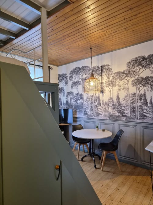 Studio Orval Et Sens Orvault avec table à manger ronde, plafond en bois et fresque murale forêt