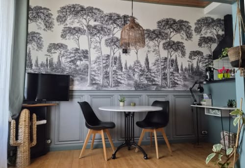Espace bureau moderne avec papier peint mural forêt, table ronde blanche, chaises noires et équipements de travail à Orval Et Sens