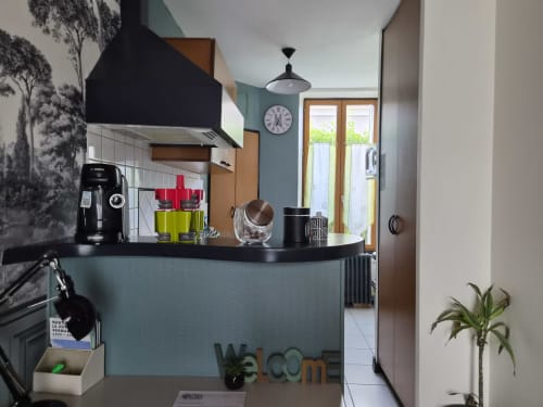 Cuisine moderne de standing à Orval Et Sens, Orvault, avec hotte noire, meubles bleu canard et portes-fenêtres sur vue ville