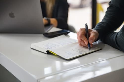 Femme d'affaires écrivant dans un carnet à l'hôtel Ô Château à Hayange, ordinateur portable à proximité