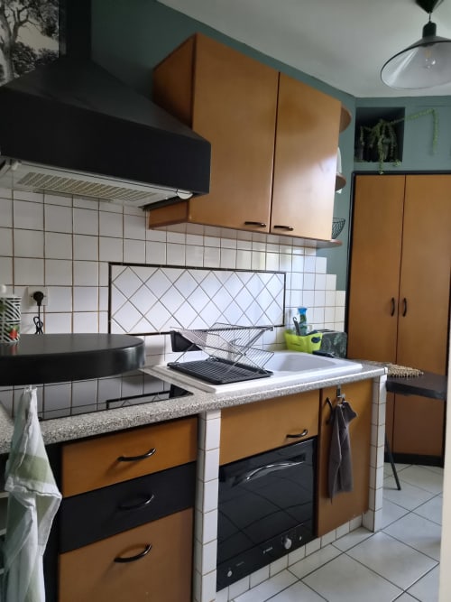 Cuisine moderne du studio Orval Et Sens avec cabinetry orange et noir, carrelage blanc et inox