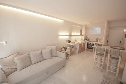 Modern open-plan hotel room at Escanda Building Solutions with cream sofa, kitchen area, and bright ambient lighting